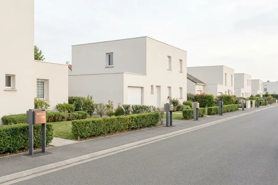 Rue pavillonnaire calme, boîtes aux lettres individuelles sur poteaux le long de haies taillées
