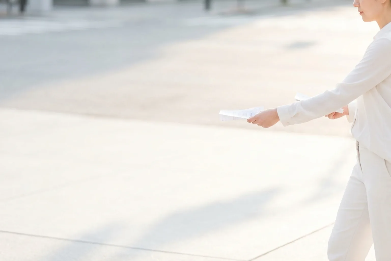 Distributeur de profil sur un trottoir ensoleillé, bras tendu présentant un imprimé plié